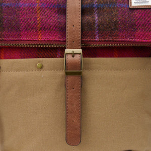 A close-up of the red tartan Harris tweed fabric on an Islander Harris tweed canvas backpack, showing a brass buckle.