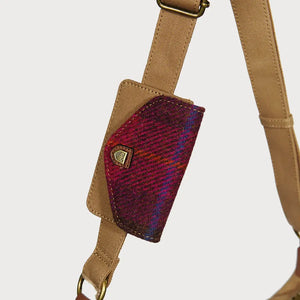 A close-up of a red tartan Harris Tweed purse attached to the shoulder strap of a red tartan Harris Tweed Luna bag.
