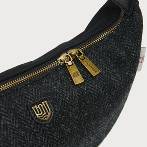 A close-up of a black herringbone Harris Tweed Luna bag, focusing on the zipper.