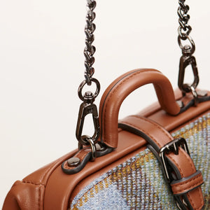 A close-up view of the Islander Harris Tweed mini doctor bag's carrying options. The image showcases the detachable shoulder strap and one of the two top handles, highlighting the materials and construction. (Islander)