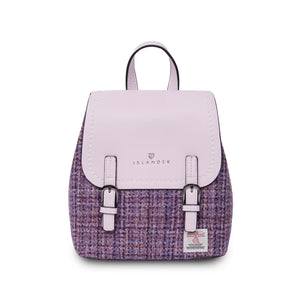 A mini Islander Violet Dogtooth Jura Backpack in Harris Tweed. This compact bag boasts a vibrant violet dogtooth pattern and features magnetic closures, adjustable straps, and a main compartment perfect for everyday essentials.