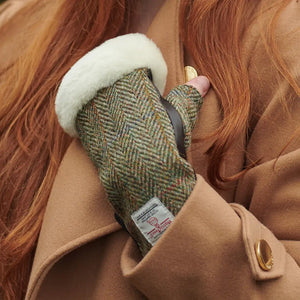 A woman wearing cozy Islander ladies sheepskin mittens with Harris Tweed, perfect for staying warm in cold weather.