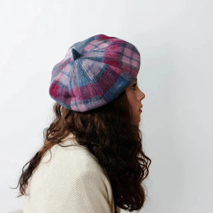Side Glance: A woman with a side grin gazes off to the side, wearing a cozy pink and blue tartan lambswool bunnet. 
