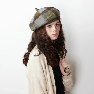 Classic Comfort: A woman bundled up in a timeless chestnut and blue tartan lambswool bunnet beams at the camera, radiating warmth and confidence.