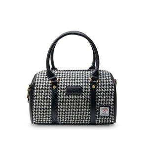 Black and white dogtooth patterned duffel bag made from Harris Tweed®, a handwoven fabric from the Scottish Outer Hebrides. The durable duffel features double zippers, a secure inner pocket, and detachable shoulder strap.