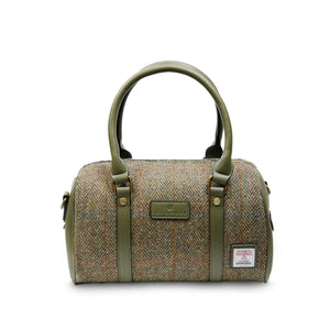 Classic herringbone patterned duffel bag in a rich chestnut color. The bag is crafted from Harris Tweed®, a durable, handwoven fabric from the Scottish Outer Hebrides. It features double zippers for easy access, a secure interior pocket, and a detachable shoulder strap for comfortable carrying.