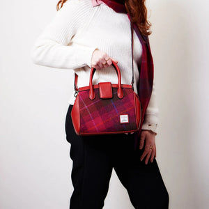 A lady wearing the Islander Red Tartan Harris Tweed Mini Tires Tote Bag using the shoulder strap but also holding the bag by the handles, handbag style. 