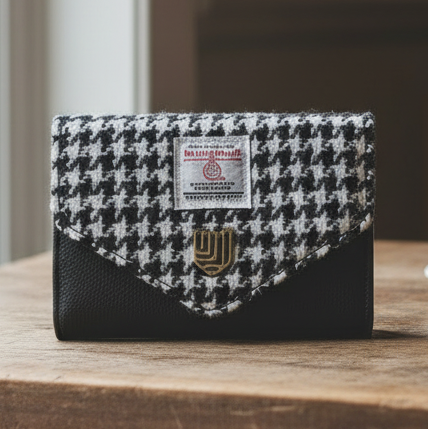 Black and white dogtooth Harris Tweed clasp purse on wooden table.