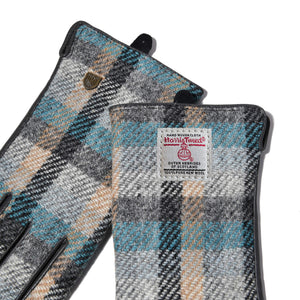 Detailed image of Harris Tweed® label on Islander tartan gloves, showing official branding and craftsmanship in soft blue and grey check.