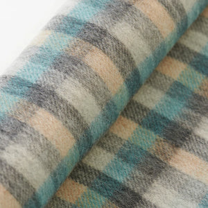 Close-up of soft Islander tartan lambswool fabric in teal and neutral tones.