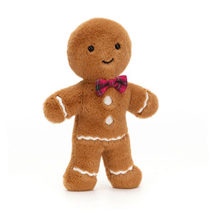 Front: A close-up photo of Jolly Gingerbread Fred, a soft plush toy from Jellycat. Fred is a golden brown gingerbread man with black button eyes, a red tartan bowtie, and a mischievous grin.