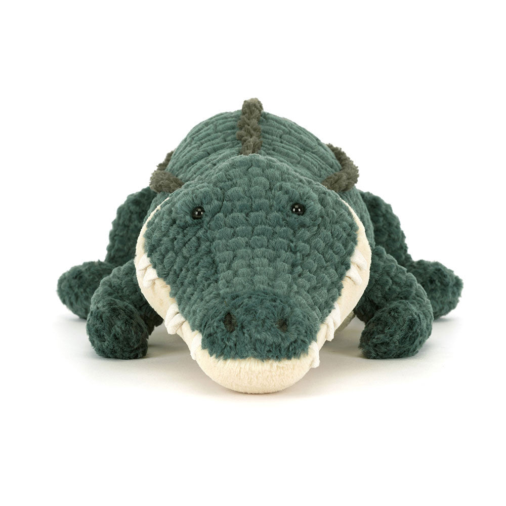 Jellycat Allexi Alligator toy on green background, angled from above to show soft corded texture, plush limbs, and toothy grin.