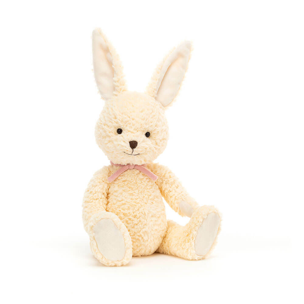 A cuddly, white bunny plush toy sitting upright, smiling with big, round eyes. The toy is made by Jellycat.