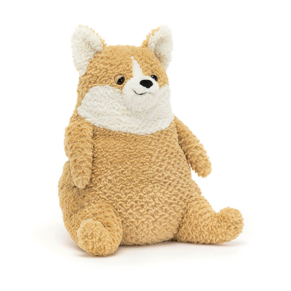 A cuddly, cream corgi plush toy sitting upright, smiling with big, round eyes. The toy is made by Jellycat.