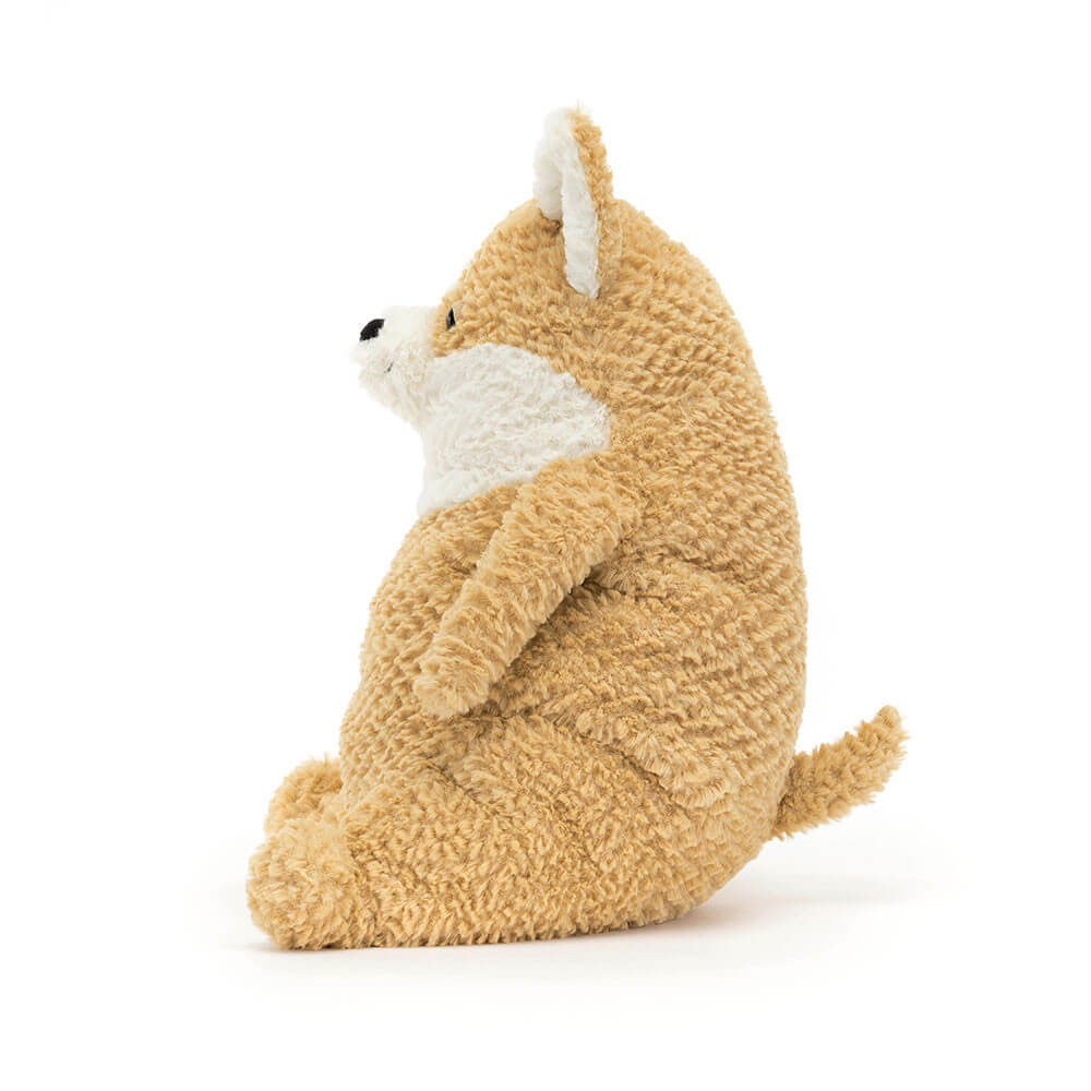 A side view of a soft, cream corgi plush toy. It is sitting down with its ears perked up. The toy is made by Jellycat.