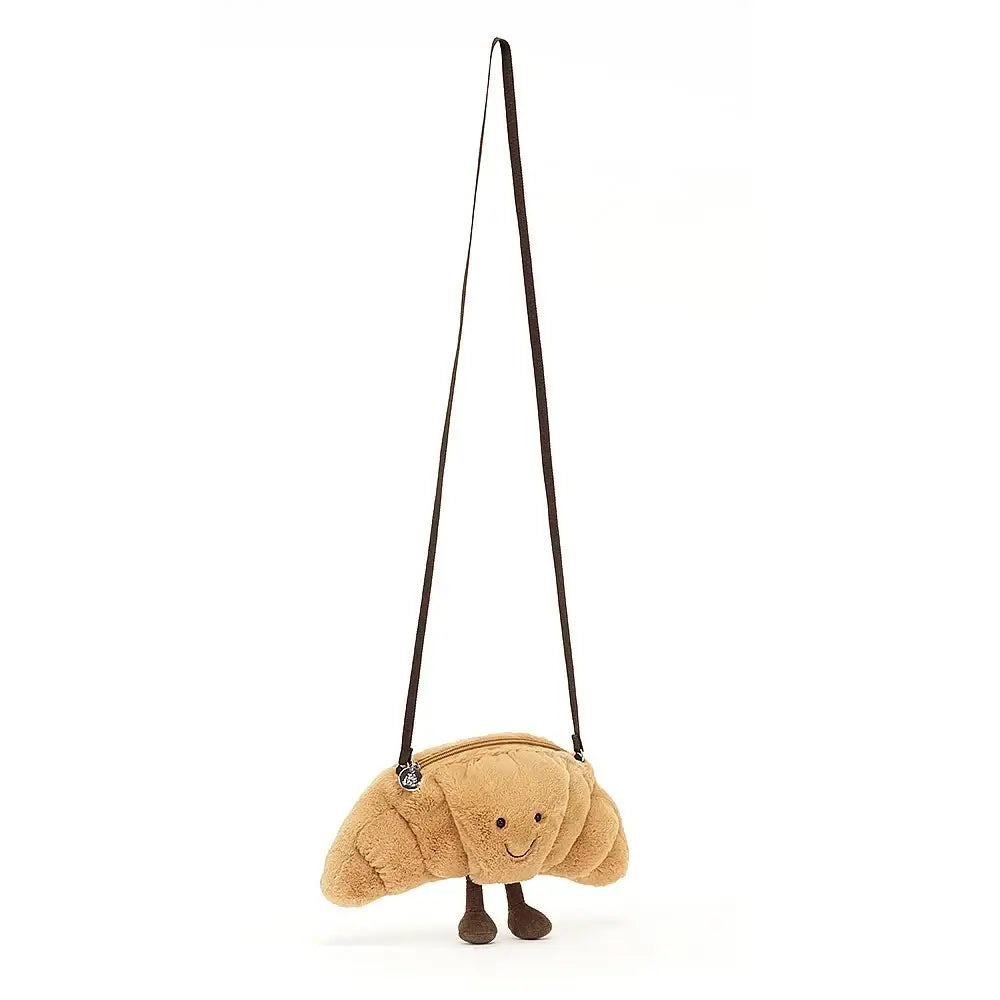 Huggable Pastry: A child gleefully cuddling the Jellycat Amuseable Croissant Bag, demonstrating its soft and huggable nature.