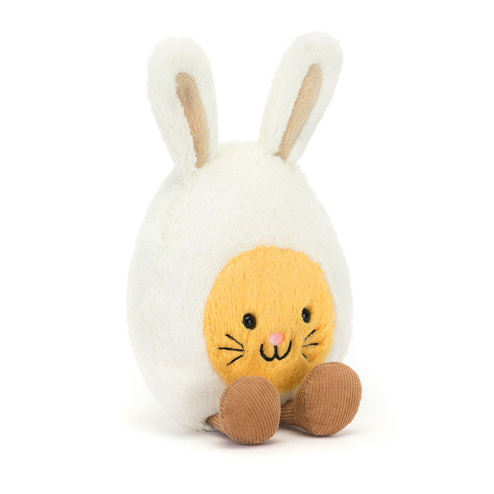 Angled view of the Jellycat Amuseables Bunny Egg showing its adorable bunny ears, smiling face, and soft, rounded shape, highlighting the plush texture and whimsical design,
