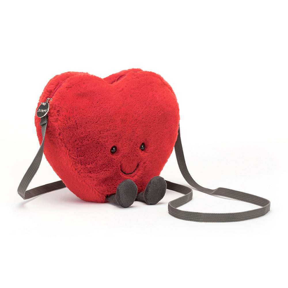 Jellycat Amuseables Heart Bag in plush red with smiling face and crossbody strap on white background.