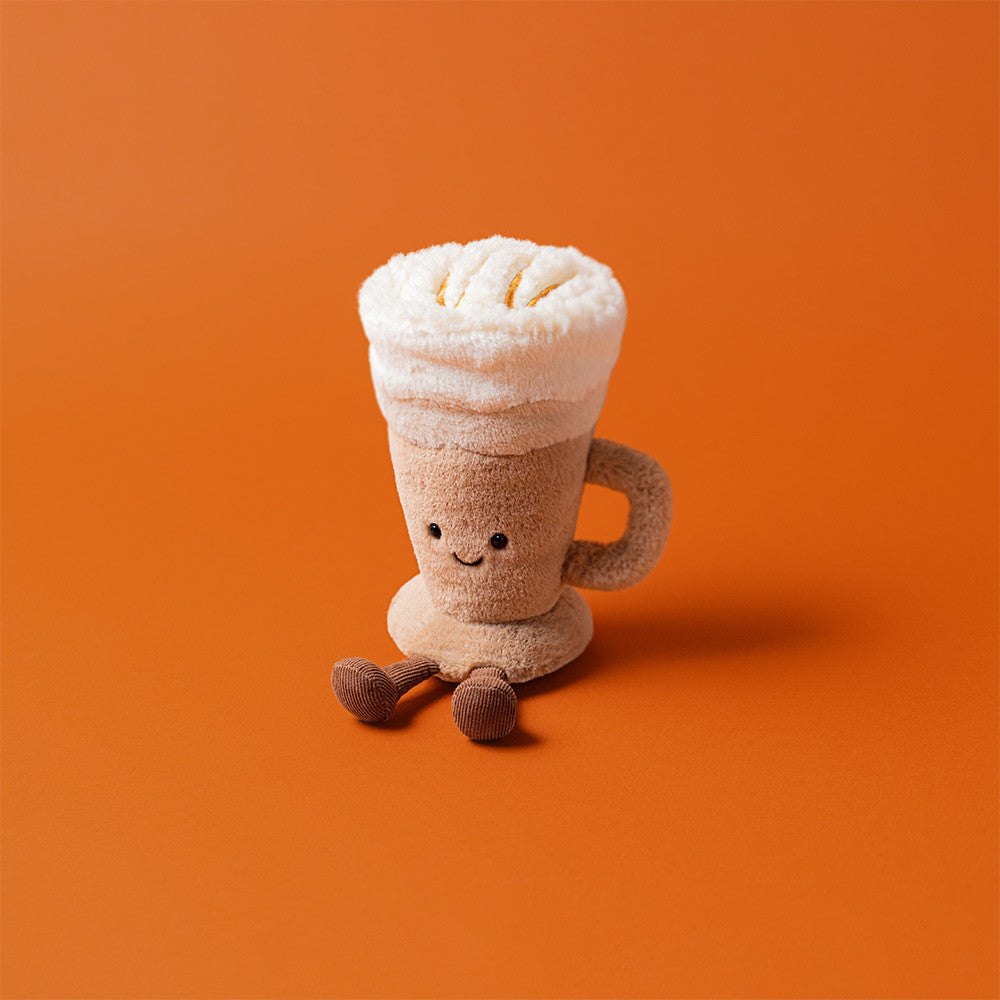 Jellycat Amuseables Latte toy on orange background, showing fluffy top and soft textures.