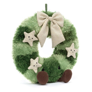 A soft, green Jellycat Amuseable Nordic Spruce Wreath adorned with pine cones, berries, and a teddy bear face.