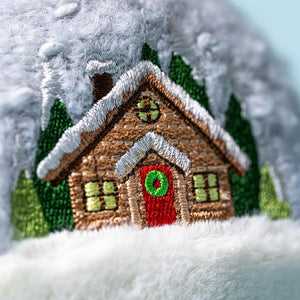 Close-up of Jellycat Snow Globe embroidery showing snowy cabin and green trees.