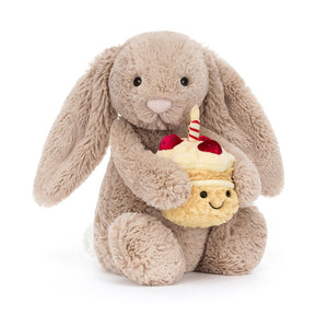 Front view of Jellycat Bashful Beige Birthday Bunny holding a birthday cupcake plush with a smiling face.