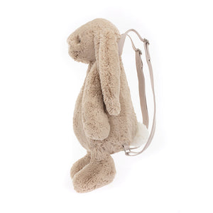 ide view of the Jellycat Bashful Beige Bunny Backpack showcasing its plush bunny design, floppy ears, and secure zip closure, with adjustable straps visible in the background.