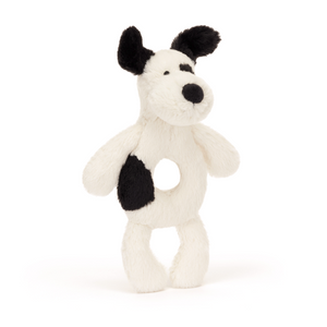 Sensory Play & Cuddles! The Jellycat Bashful Black & Cream Puppy Ring Rattle, with its floppy ears and hidden rattle, encourages grasping and auditory development. (Angled view)