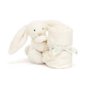 Sidekick for Sweet Dreams: The Jellycat Bashful Cream Bunny Soother's bunny friend sits beside its rolled-up blanket, offering comfort and security throughout the night.