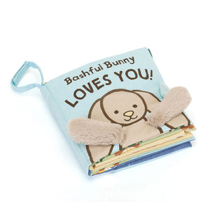  Angled View:  Jellycat Bashful Bunny Loves You: A huggable 15 cm x 15 cm cloth book with soft textures, lift-up flaps, and adorable floppy ears to engage your baby's senses.
