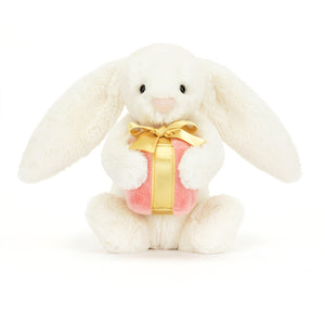 Front-On: Soft and floppy Jellycat Bashful Bunny cradles a beautifully wrapped present, perfect for gifting or cuddling.