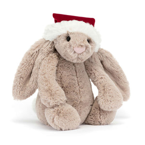 Angled View:  A Christmas Cuddle Classic! The Jellycat Bashful Christmas Bunny with soft fur, long ears & a red holiday hat.