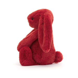 Side View: A side view of a cuddly cranberry-coloured Christmas bunny toy, showcasing its three-dimensional shape and the details of its outfit.