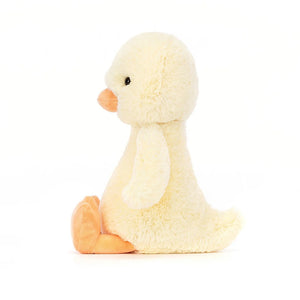 Jellycat Bashful Duckling in a side sitting position showing a cute orange beak and feet with a soft primrose yellow fur.