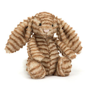 Angled View: Golden cuddles await! The Jellycat Bashful Luxe Bunny Juniper sits tilted, showcasing its toasty golden-brown fur with ombre stripes. Floppy cream ears and fluffy paws.