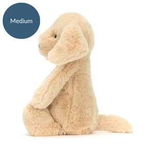 Side view of Jellycat Bashful Luxe Puppy Orlando (Medium), a soft beige plush puppy with floppy ears and a cuddly body.