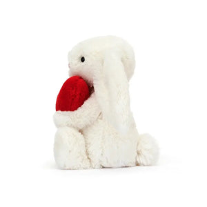 Melt hearts with the Jellycat Bashful Red Love Heart Bunny's huggable profile. Creamy fur, floppy ears, and a held heart make it a timeless gift. 