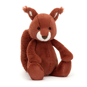 Angled View: Looking for a nut-loving buddy? The Jellycat Bashful Squirrel sits tilted, showcasing its warm rusty fur with a hint of floof, silky tuft ears, a creamy white muzzle, and a cocoa suedette nose. Don't forget the impressive tail!