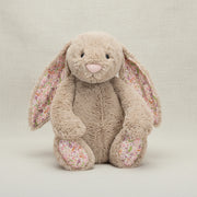 Jellycat Blossom Beige Bunny ‘Petal’ displayed at an angle, showcasing its soft beige fur and floral-patterned ears and paws.