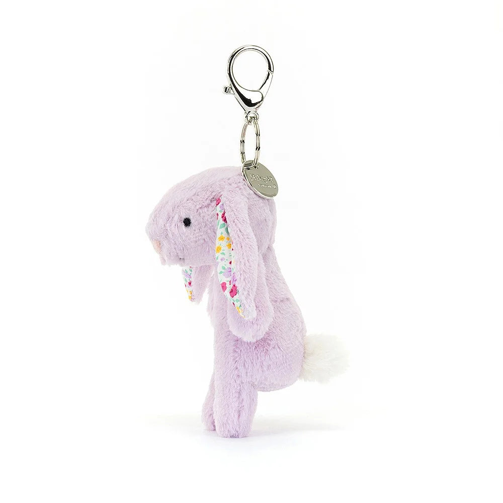 Playful Jellycat Jasmine Bunny charm shows off fluffy tail & colorful ears - a whimsical touch for any bag or backpack.