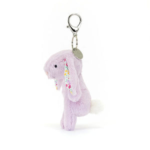 Playful Jellycat Jasmine Bunny charm shows off fluffy tail & colorful ears - a whimsical touch for any bag or backpack.
