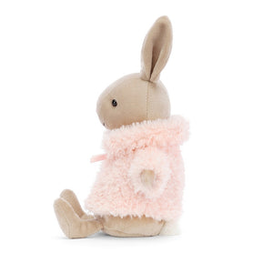 Side view of Jellycat Comfy Coat Bunny, showcasing its textured pink coat, long ears, and rounded profile.