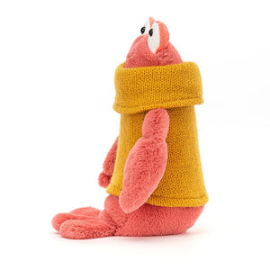 A charming Jellycat Cozy Crew Lobster in profile, showcasing his long, split tail and cozy mustard rollneck jumper. The soft, peachy-pink plush with squidgy segments adds to his cuddly appeal.
