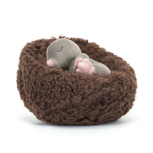 Angled View: Jellycat Hibernating Mole peeking out of its cozy, fleecy cocoa bed at an angle. Soft grey fur, pink nose, and embroidered closed eyes create a picture of sleepy curiosity.