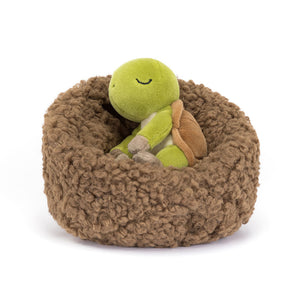 Adorable Jellycat Hibernating Tortoise plush toy, angled view, showcasing its sleepy expression and cosy nest.