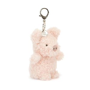 Jellycat Little Pig Bag Charm, a small, plush pig keychain with soft pink fur, fuzzy hooves, and an embroidered snout. The pig is standing upright with a playful expression.