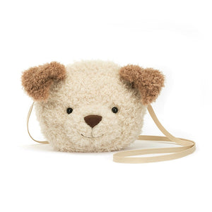 Jellycat Little Pup Bag, a small, cream and toffee plush bag shaped like a dogs head with soft fur, floppy ears, and a playful expression. The bag has adjustable straps.