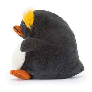 Soft Jellycat Maurice Macaroni penguin plush: Side view showing blue-grey fur, yellow tufts & orange beak & feet.