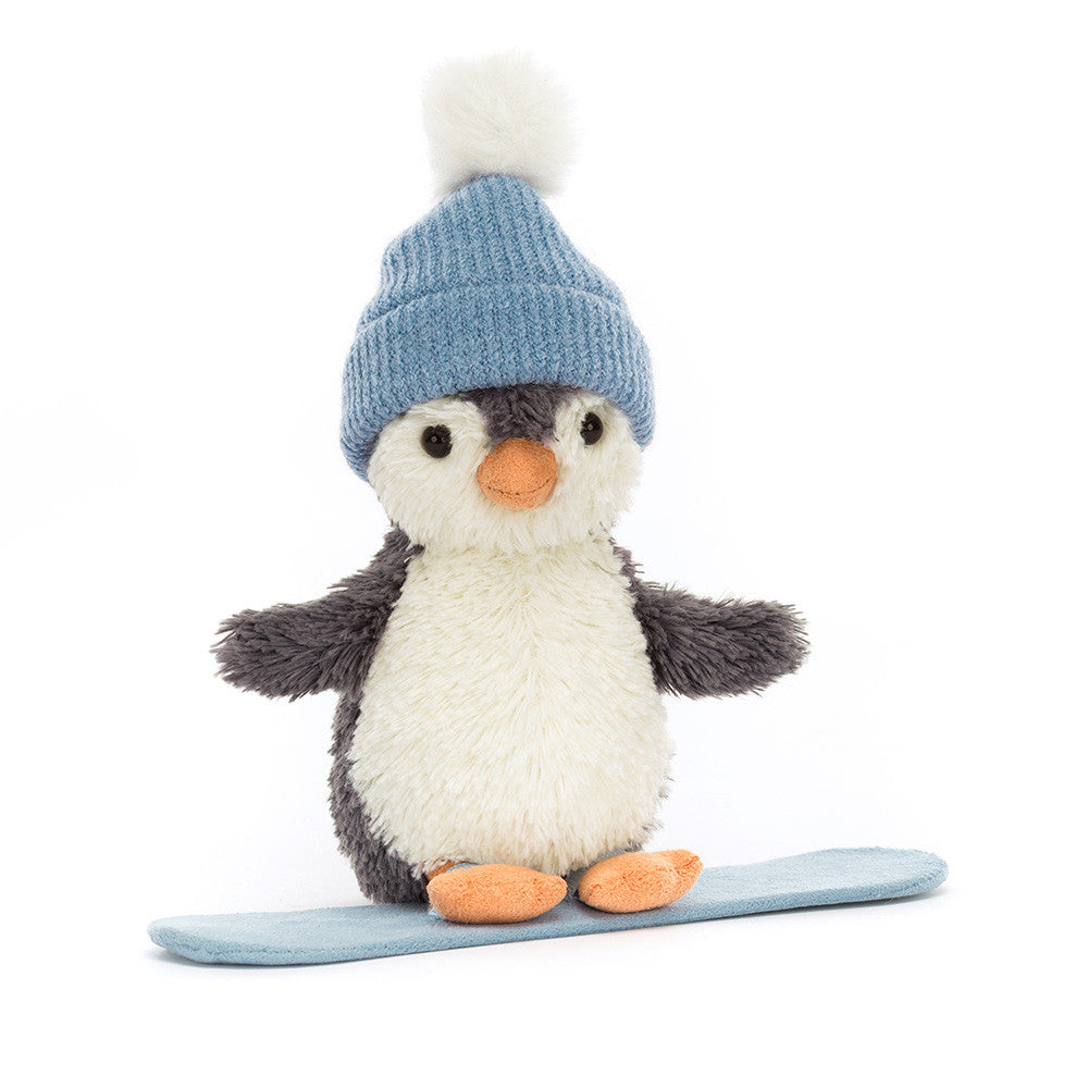 Jellycat Peanut Penguin Snowboarding soft toy wearing a blue pom-pom hat standing on a blue snowboard.