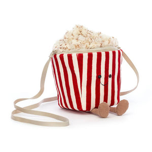 Adorable Jellycat Popcorn Bag with plush popcorn pieces spilling out and shoulder strap playfully wrapped around. Perfect for carrying your favorite snacks or cuddly friends on the go!